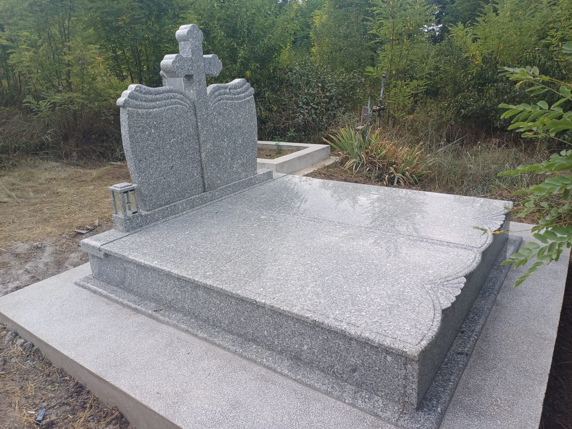 Monument funerar dublu din piatră, model cu cruce centrală și detalii sculptate
