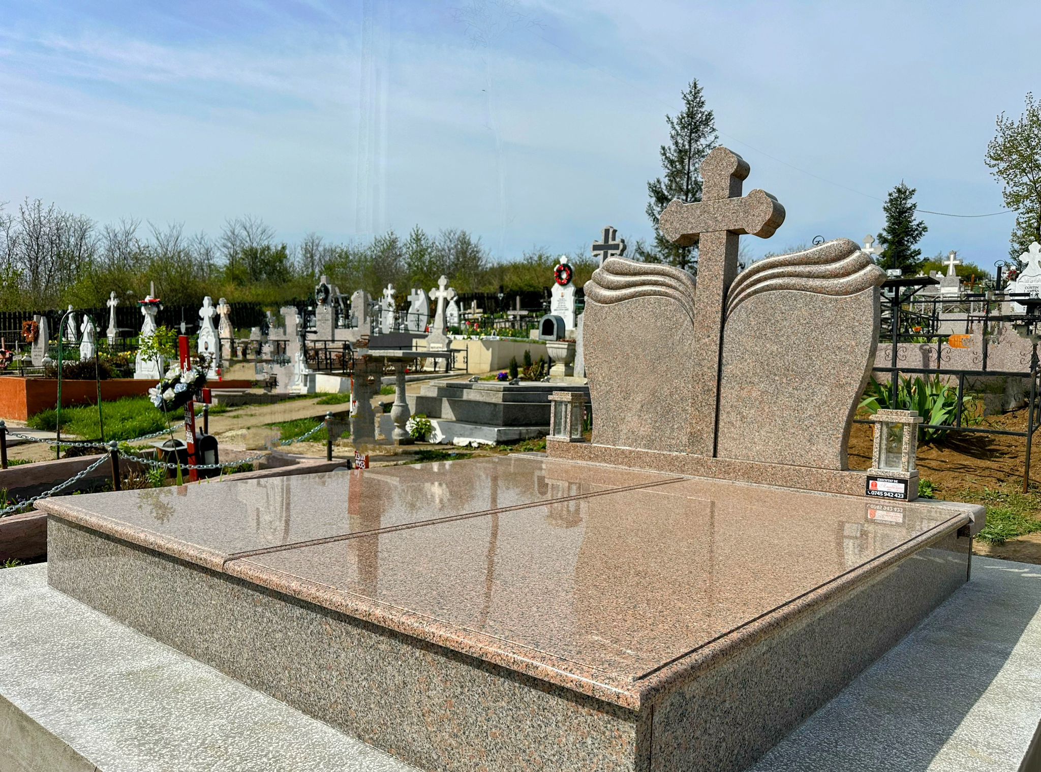 Monument funerar dublu în nuanță caldă, cu cruce centrală